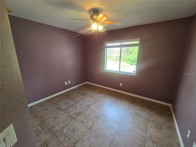 empty room featuring ceiling fan and baseboards