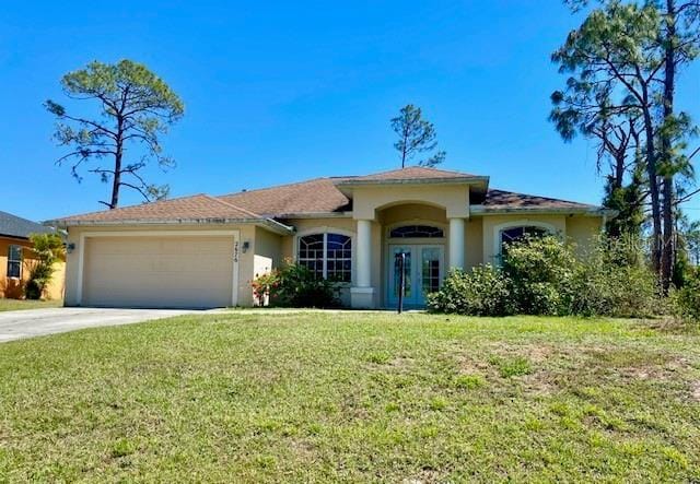 mediterranean / spanish-style home with stucco siding, driveway, french doors, a front yard, and an attached garage