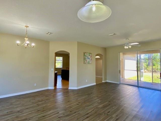 spare room featuring dark wood-type flooring, baseboards, and arched walkways