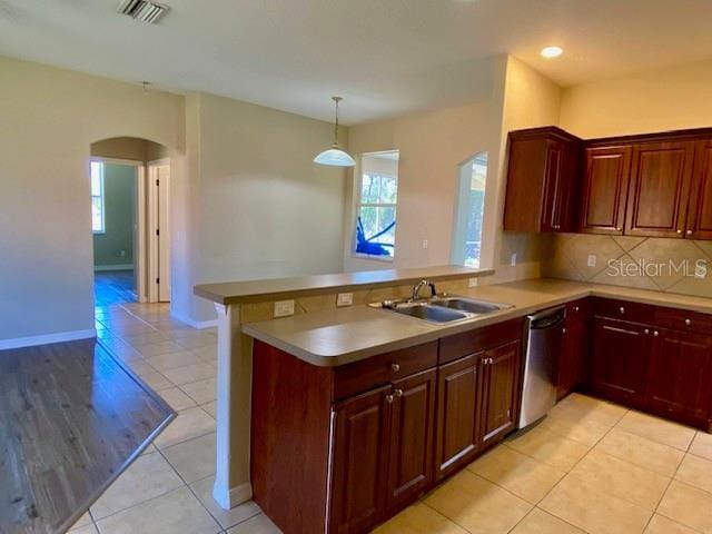 kitchen featuring visible vents, dishwasher, a peninsula, arched walkways, and a sink