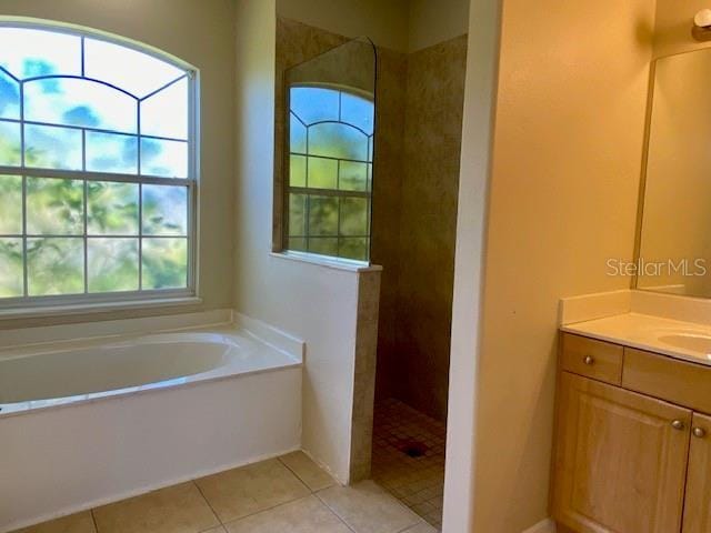 bathroom with tile patterned flooring, a walk in shower, vanity, and a garden tub