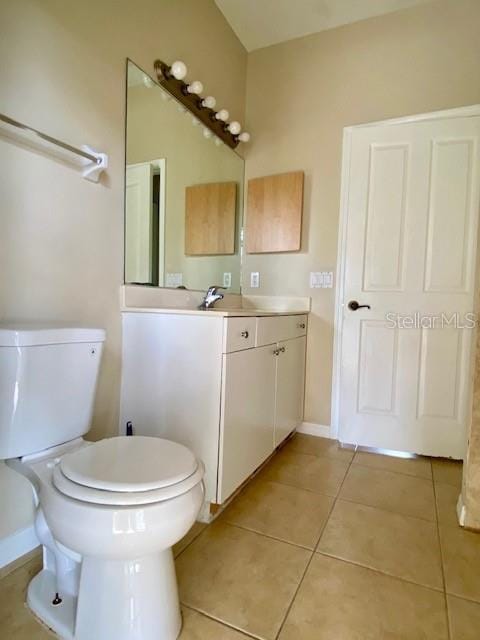 bathroom featuring tile patterned floors, baseboards, toilet, and vanity