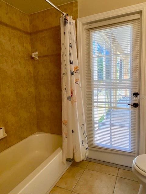 bathroom featuring tile patterned floors, toilet, and shower / bathtub combination with curtain