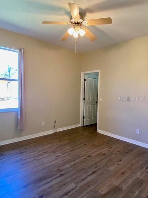 unfurnished room featuring ceiling fan, baseboards, and dark wood-style floors