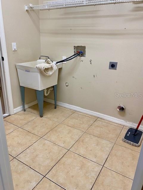 washroom featuring electric dryer hookup, washer hookup, hookup for a gas dryer, light tile patterned floors, and laundry area