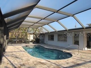 outdoor pool with glass enclosure and a patio area