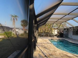 outdoor pool with glass enclosure and a patio