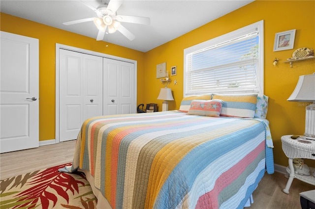 bedroom featuring a closet, wood finished floors, a ceiling fan, and baseboards