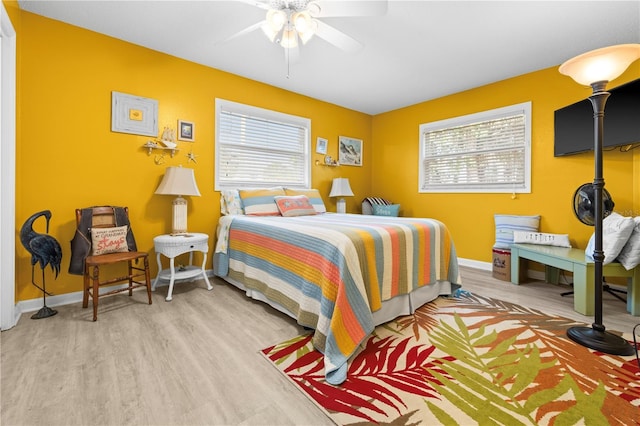 bedroom featuring multiple windows, baseboards, and wood finished floors