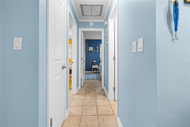 hall with visible vents, crown molding, baseboards, and light tile patterned floors