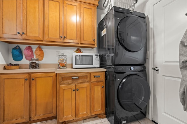 washroom with stacked washing maching and dryer, light tile patterned floors, and cabinet space