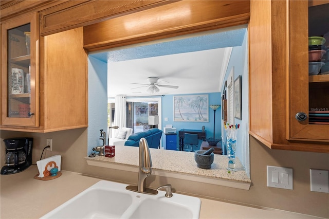 kitchen with brown cabinets, glass insert cabinets, light countertops, and a sink