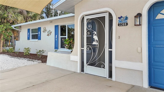 view of exterior entry featuring a garage and stucco siding