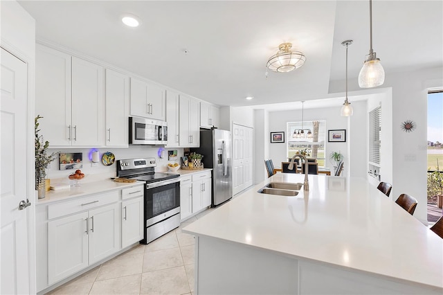 kitchen with a large island with sink, stainless steel appliances, a sink, and light countertops