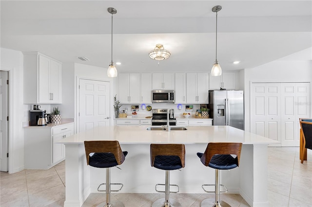 kitchen with light countertops, appliances with stainless steel finishes, white cabinets, light tile patterned flooring, and a sink