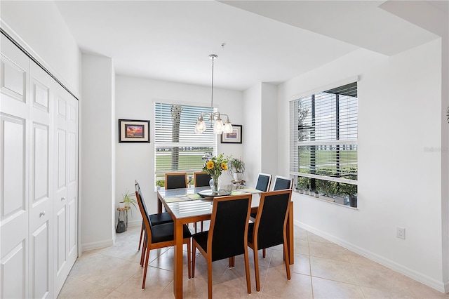 dining area with a chandelier, baseboards, and light tile patterned floors