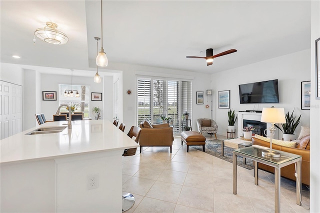 living area featuring light tile patterned floors, ceiling fan, and a glass covered fireplace