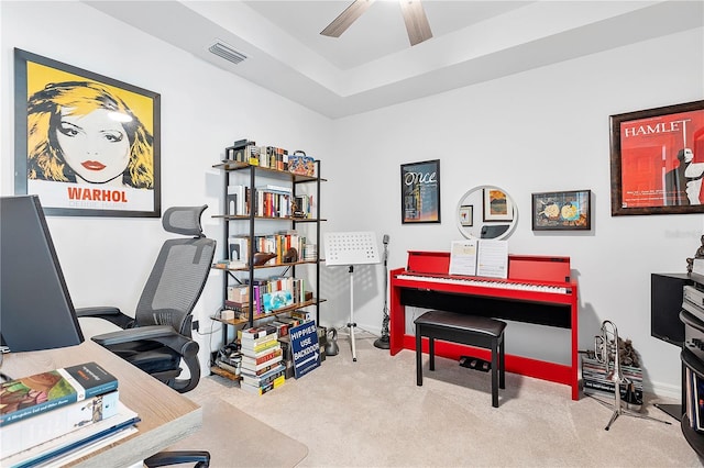 home office featuring carpet floors, a tray ceiling, visible vents, and a ceiling fan