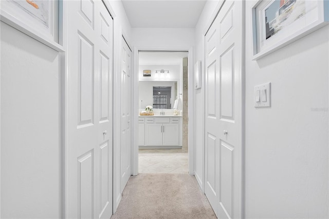 corridor with a sink and light colored carpet