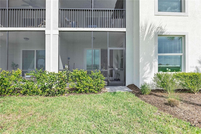 property entrance with a yard, a balcony, and stucco siding