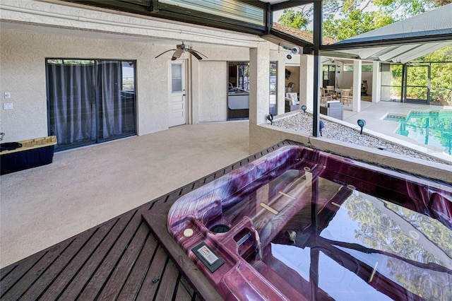 exterior space with ceiling fan, glass enclosure, a patio, and a hot tub