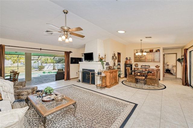 living room with light tile patterned floors, a fireplace, vaulted ceiling, and ceiling fan with notable chandelier