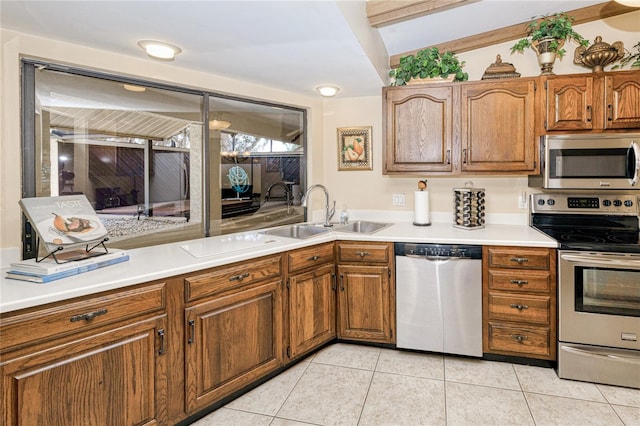 kitchen featuring appliances with stainless steel finishes, brown cabinets, a sink, and light tile patterned floors