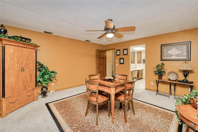 dining room with baseboards, visible vents, and light colored carpet