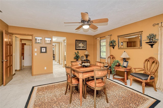 dining space featuring light carpet, ceiling fan, light tile patterned floors, and a textured ceiling