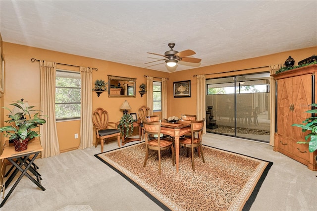 dining space with a textured ceiling, ceiling fan, and light colored carpet