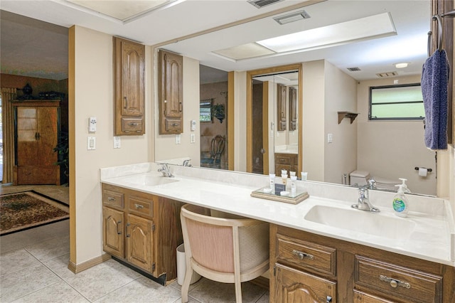 bathroom with double vanity, a sink, toilet, and tile patterned floors