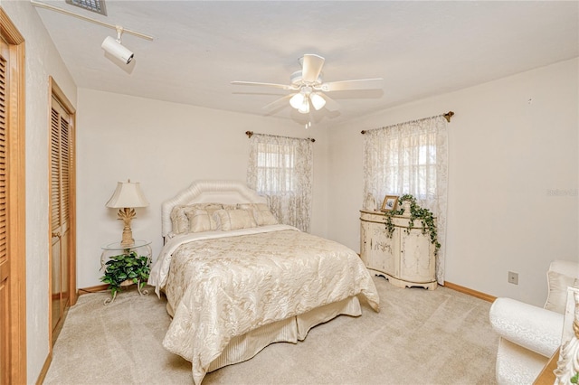 bedroom with light carpet, a closet, a ceiling fan, and baseboards