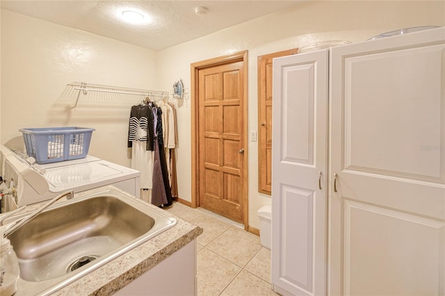 clothes washing area featuring laundry area, light tile patterned floors, baseboards, washing machine and dryer, and a sink