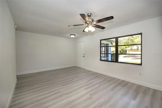 unfurnished room with baseboards, a textured ceiling, a ceiling fan, and light wood-style floors