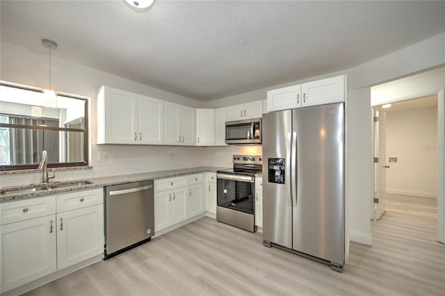 kitchen with white cabinetry, appliances with stainless steel finishes, backsplash, and a sink