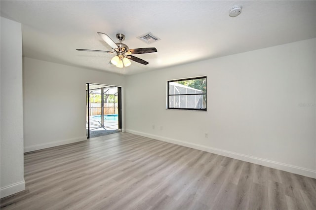 spare room with ceiling fan, light wood finished floors, visible vents, and baseboards