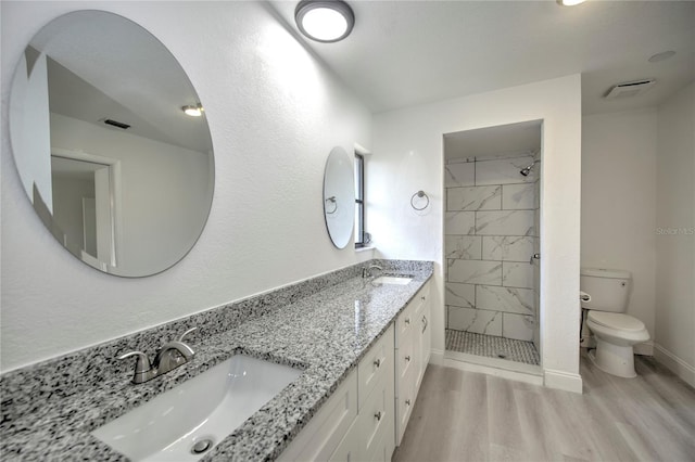 bathroom featuring a sink, a shower stall, toilet, and wood finished floors