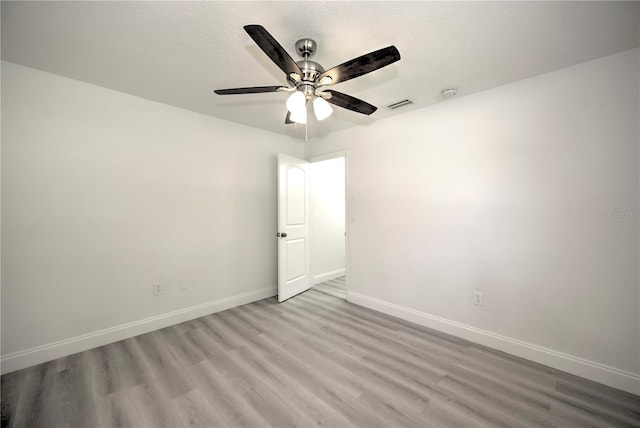 unfurnished room featuring a ceiling fan, wood finished floors, visible vents, and baseboards