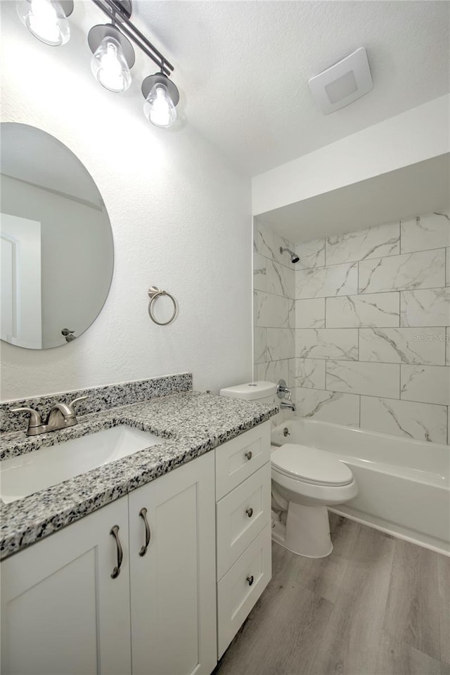 bathroom featuring toilet, wood finished floors, a textured ceiling, vanity, and shower / washtub combination