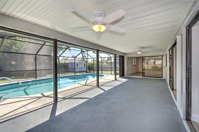 view of swimming pool featuring a patio area, a fenced in pool, glass enclosure, and a ceiling fan