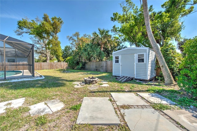 view of yard featuring a fenced in pool, an outbuilding, a lanai, a fenced backyard, and a fire pit