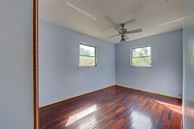 spare room with a wealth of natural light, wood-type flooring, a textured ceiling, and baseboards