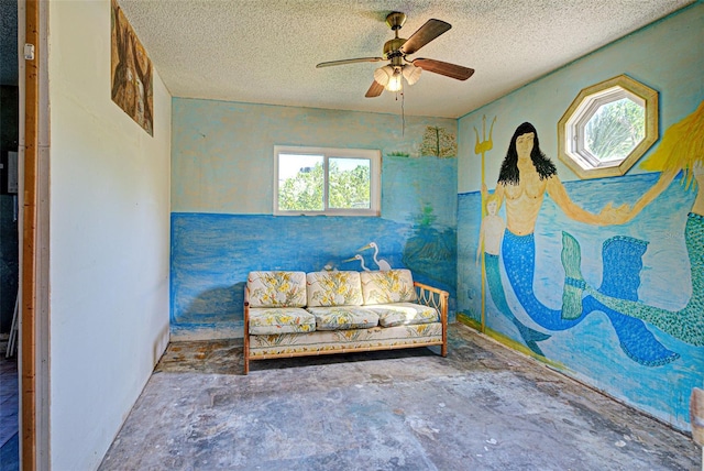 sitting room featuring unfinished concrete flooring, ceiling fan, and a textured ceiling