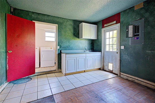 kitchen with electric panel, a textured ceiling, washing machine and dryer, white cabinetry, and a sink