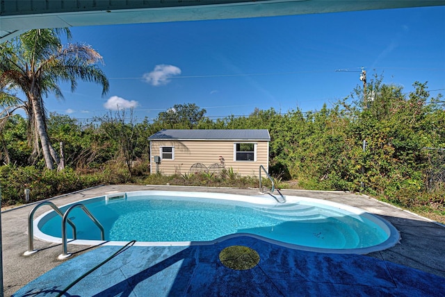 outdoor pool featuring an outbuilding and a patio area