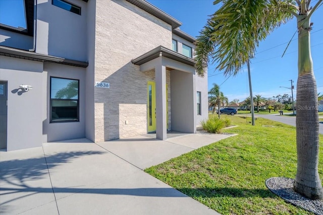 doorway to property with a lawn and stucco siding