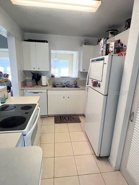 kitchen with white appliances, white cabinetry, light countertops, and light tile patterned flooring