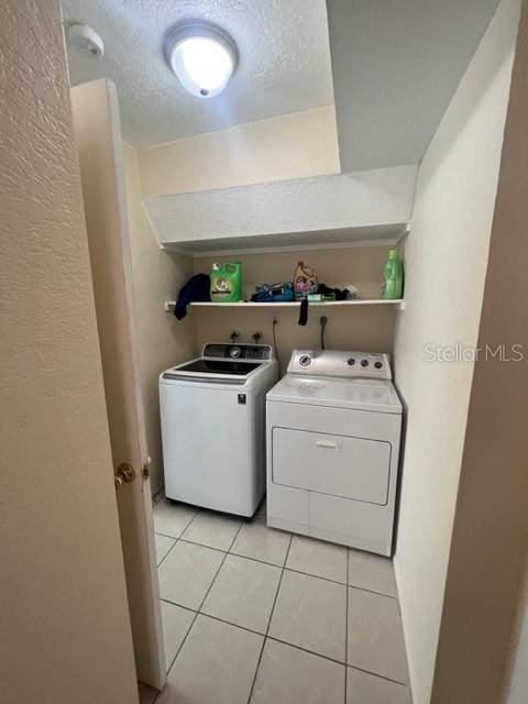 laundry area with laundry area, light tile patterned flooring, independent washer and dryer, and a textured ceiling