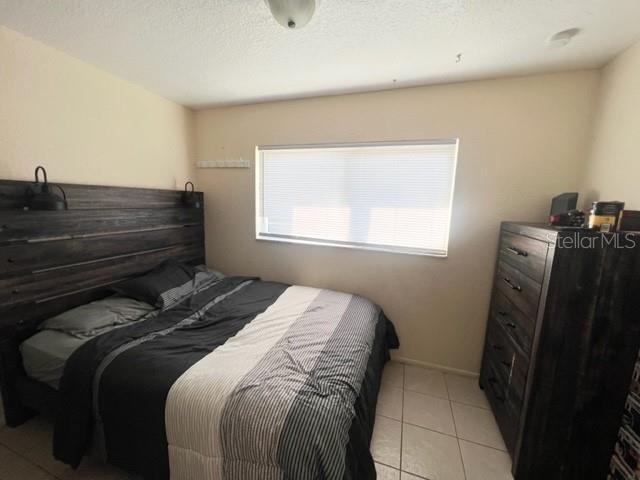 bedroom with a textured ceiling and light tile patterned floors