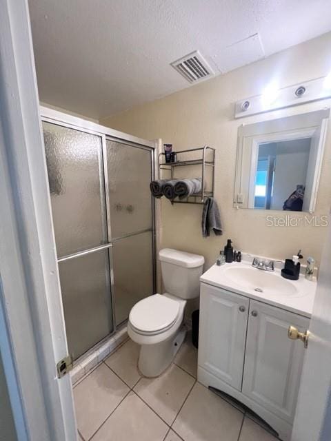 bathroom with toilet, vanity, visible vents, tile patterned floors, and a stall shower